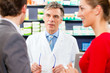 Pharmacist with customers in pharmacy