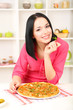 Beautiful girl with delicious pizza on kitchen background