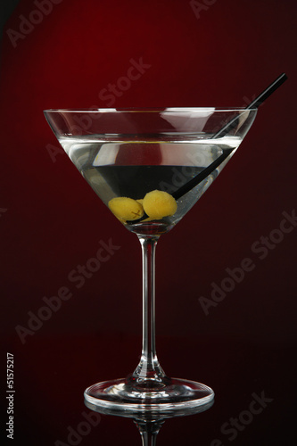 Photo: Martini glass with olives on dark red background Martini glass with olives on dark red background