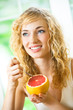 Cheerful blond woman eating grapefruit