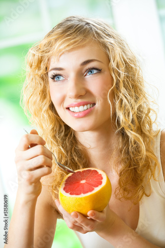 Photo: Cheerful blond woman eating grapefruit Cheerful blond woman eating grapefruit