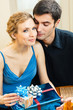 Cheerful amorous couple with gifts, indoors