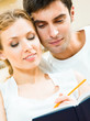 Foto: Cheerful couple with organizer, indoors Cheerful couple with organizer, indoors