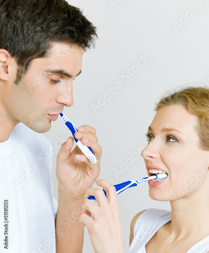 Photo: Cheerful young couple cleaning teeth together Cheerful young couple cleaning teeth together