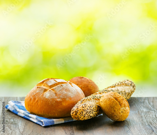 Photo: Fresh bread and checkered napkin on wooden table on rural backgr Fresh bread and checkered napkin on wooden table on rural backgr