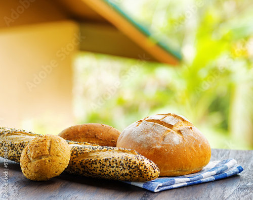 Photo: Fresh bread and checkered napkin on wooden table on rural backgr Fresh bread and checkered napkin on wooden table on rural backgr
