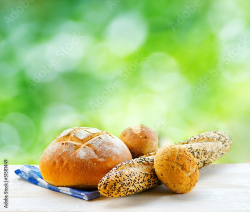 Photo: Fresh bread and checkered napkin on wooden table on rural backgr Fresh bread and checkered napkin on wooden table on rural backgr