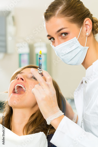 Photo: Zahnarzt hält eine Spritze - Narkose bei einer Patientin Zahnarzt hält eine Spritze - Narkose bei einer Patientin