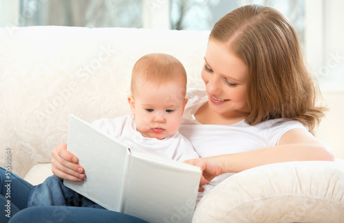 Photo: Mother reading a book a little baby on the sofa Mother reading a book a little baby on the sofa