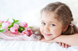 Little girl lying with pink tulips