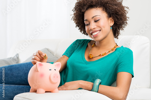 Photo: Woman Putting Coin In Piggybank Woman Putting Coin In Piggybank