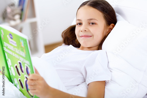 Photo: Girl with a book in bed at home Girl with a book in bed at home