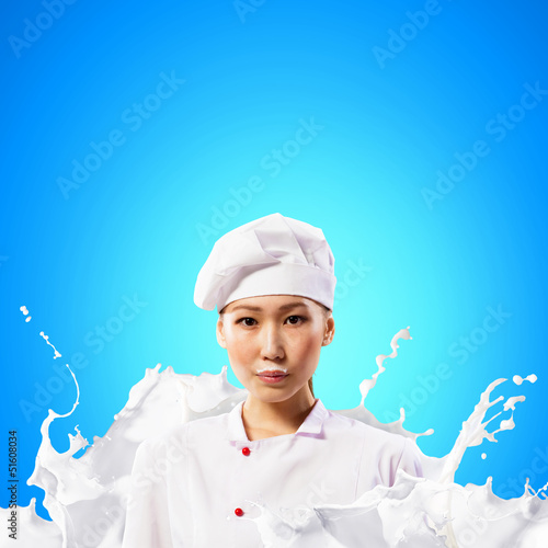 Photo: Asian female cook against milk splashes Asian female cook against milk splashes