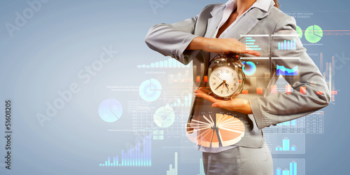 Photo: Business woman holding alarmclock Business woman holding alarmclock
