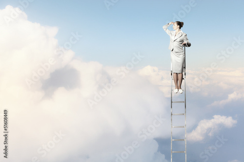 Photo: Businesswoman standing on ladder Businesswoman standing on ladder