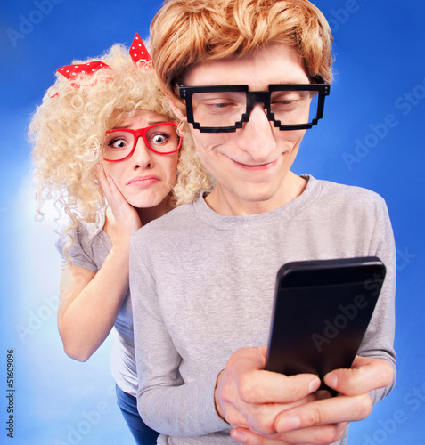 Photo: Girl is spying on boyfriend he is using a smart phone Girl is spying on boyfriend he is using a smart phone