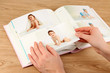 Photos in hands and photo album on wooden table