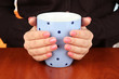Hands holding mug of hot drink, close-up
