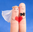 wedding concept -  newlyweds painted at fingers against blue sky