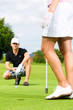 Foto: Young sportive couple playing golf on a course Young sportive couple playing golf on a course