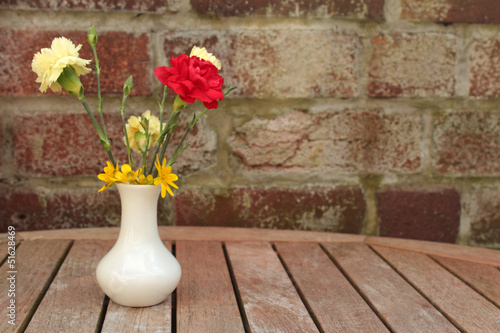 Photo: Flowers in little white vase on garden table Flowers in little white vase on garden table