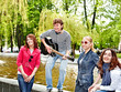 Photo: Group of people in city park listen music. Group of people in city park listen music.