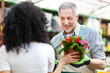 Woman choosing flowers in a greenhouse with an employee