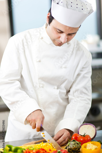 Photo: Young chef cutting vegetables in a kitchen Young chef cutting vegetables in a kitchen
