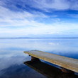 Concrete pier or jetty and on a blue lake and sky reflection.