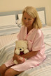 Seniorin sitzt auf einem Bett mit Teddybär