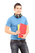 A handsome student with headphones holding books