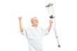 A happy mature patient holding crutches and gesturing happiness