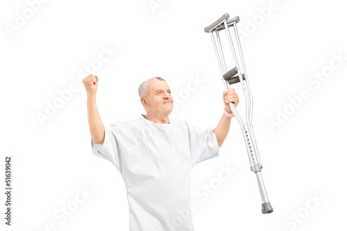 Photo: A happy mature patient holding crutches and gesturing happiness A happy mature patient holding crutches and gesturing happiness
