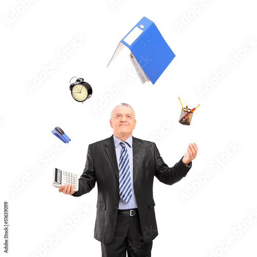 Photo: Mature man in a suit juggling with office supplies Mature man in a suit juggling with office supplies