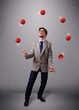 young man standing and juggling with red balls