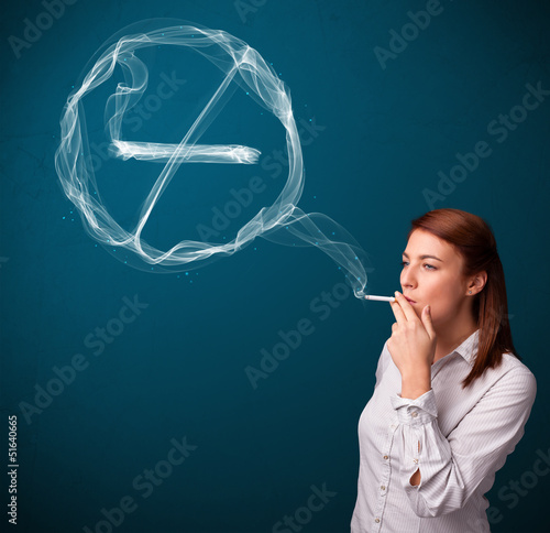 Photo: Young lady smoking unhealthy cigarette with no smoking sign Young lady smoking unhealthy cigarette with no smoking sign
