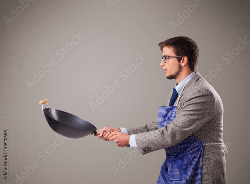 Photo: Young man holding a black frying pan Young man holding a black frying pan