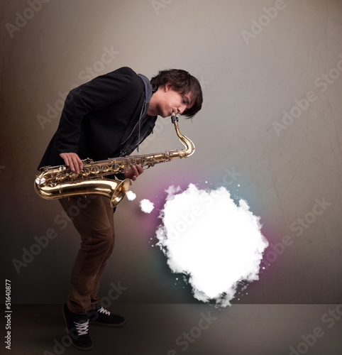 Photo: Young man playing on saxophone with copy space in white cloud Young man playing on saxophone with copy space in white cloud