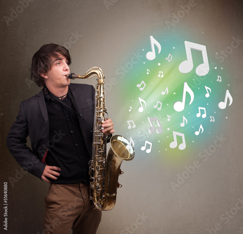 Photo: Young musician playing on saxophone while musical notes explodin Young musician playing on saxophone while musical notes explodin