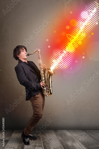 Photo: Young man playing on saxophone with colorful sound waves Young man playing on saxophone with colorful sound waves