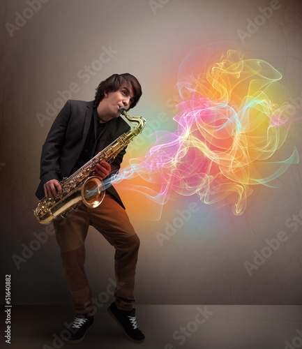 Photo: Attractive musician playing on saxophone with colorful abstract Attractive musician playing on saxophone with colorful abstract