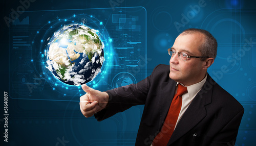 Photo: Businessman touching high-tech 3d earth panel Businessman touching high-tech 3d earth panel