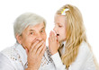girl telling an astonished old woman some secrets. isolated 