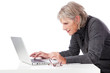 seniorin schaut konzentriert auf laptop