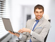young businessman sitting in chair with laptop