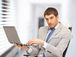 young businessman sitting in chair with laptop