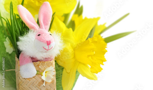Photo: Cute pink bunny with yellow daffodil flowers. Cute pink bunny with yellow daffodil flowers.