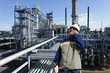 oil worker with large refinery in background