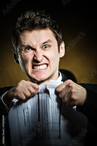 Photo: Angry businessman tearing document Angry businessman tearing document