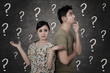 Photo: Confused couple with question marks on blackboard Confused couple with question marks on blackboard